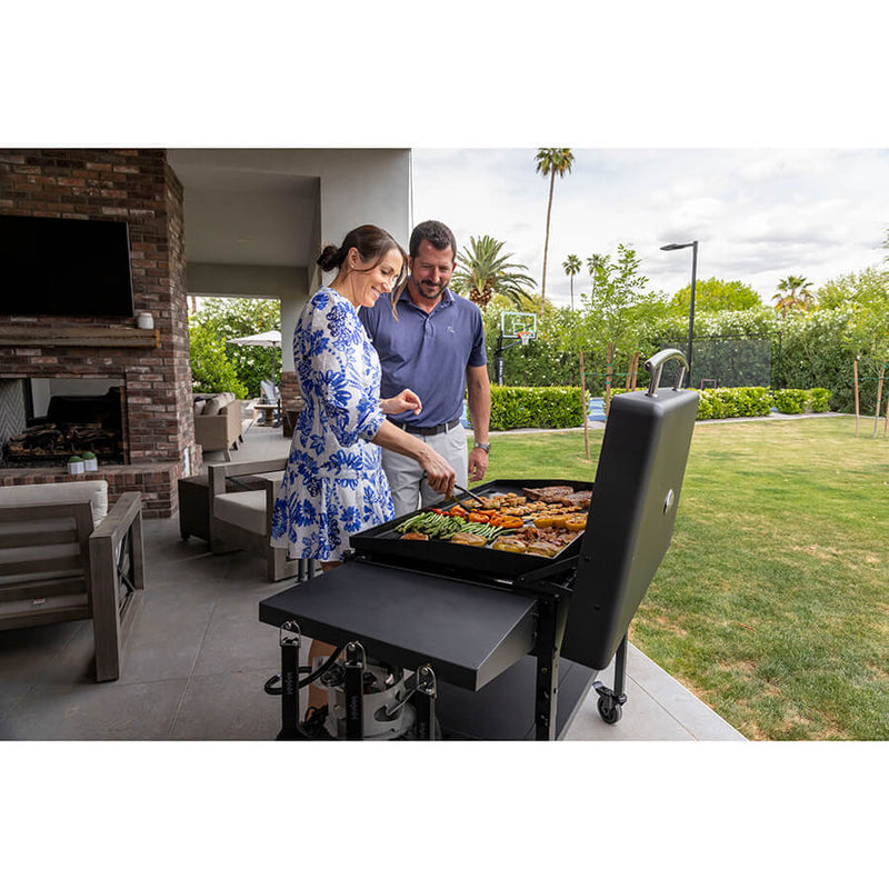 Louisiana Grills 4-Burner Gas Griddle with Ceramic Top. Couple cooking food in family home backyard